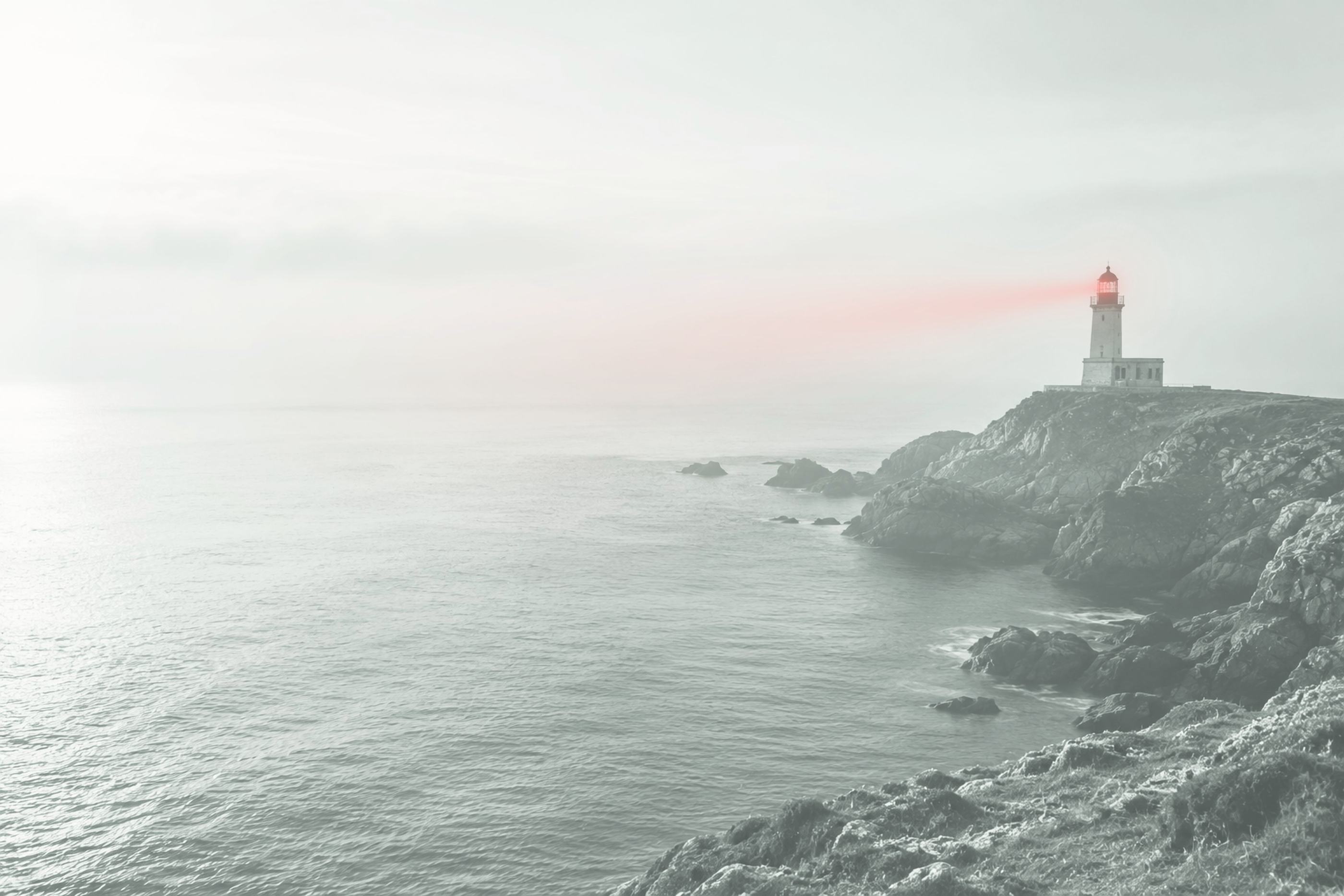 Lighthouse on a cliff casting a beam of light out to sea